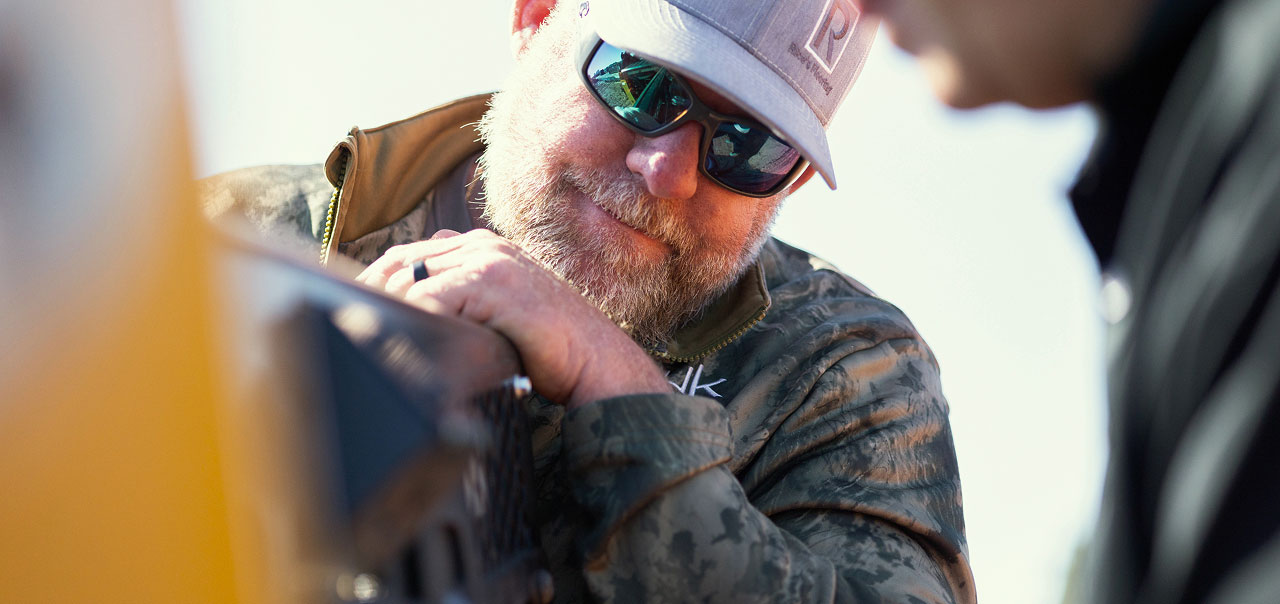 Man in sunglasses and cap looking at equipment