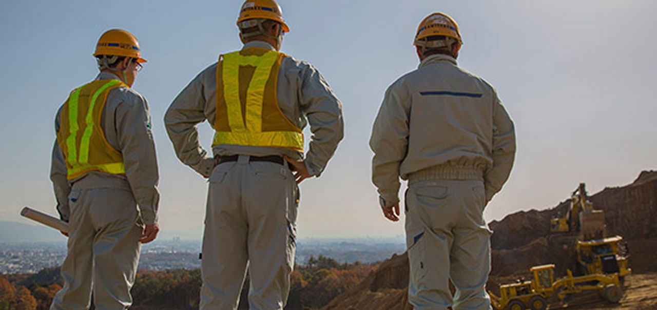 Three men in work gear looking away